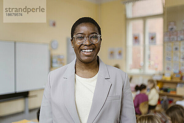 Porträt einer glücklichen Lehrerin mit Blazer im Klassenzimmer