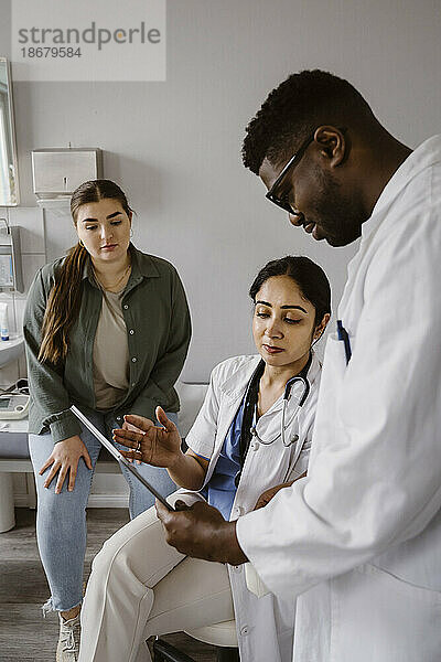 Arzt erklärt männlichen Kollegen über Tablet-PC in der Klinik