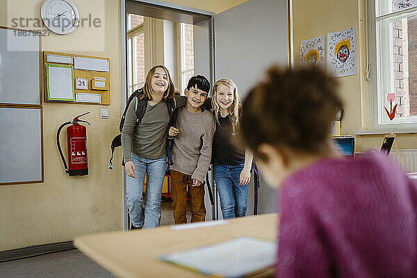 Glückliche Freunde  die sich umarmen  wenn sie das Klassenzimmer betreten