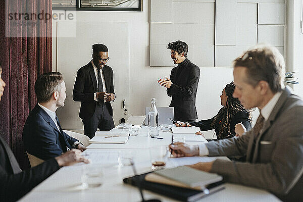 Glückliche männliche Unternehmer  die während eines Geschäftstreffens im Büro diskutieren