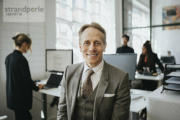 Porträt eines lächelnden reifen Geschäftsmannes im Anzug im Büro