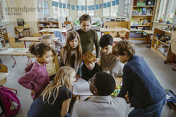 Schüler betrachten den Lehrer  der ihnen im Klassenzimmer hilft