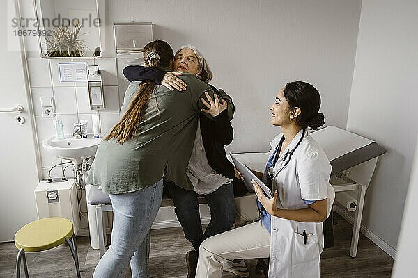 Tochter  die ihre Mutter umarmt  die auf dem Bett der Tochter in der Klinik sitzt