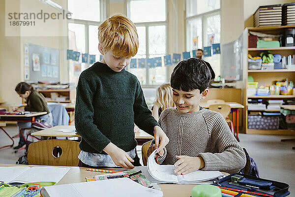Jungen teilen ein Buch beim Lernen im Klassenzimmer