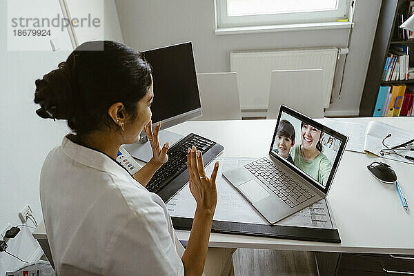 Hohe Winkel Ansicht der weiblichen Kinderarzt winken Patienten über Video-Anruf durch Laptop am Schreibtisch in der Klinik