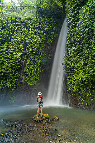 Blick auf eine Frau  die am Melanting-Wasserfall  Kabupaten Buleleng  Gobleg  Bali  Indonesien  Südostasien  Asien fotografiert