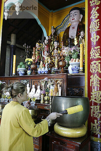 Rong Thanh Temple  Vietnamese Buddhist woman using a giant singing bowl  Tan Chau  Vietnam  Indochina  Southeast Asia  Asia