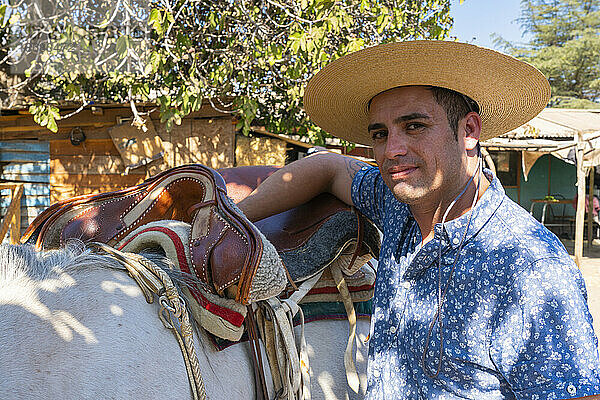 Junger chilenischer Reiter (Huaso) bereitet weißes Pferd auf Ranch  Colina  Provinz Chacabuco  Metropolregion Santiago  Chile  Südamerika vor