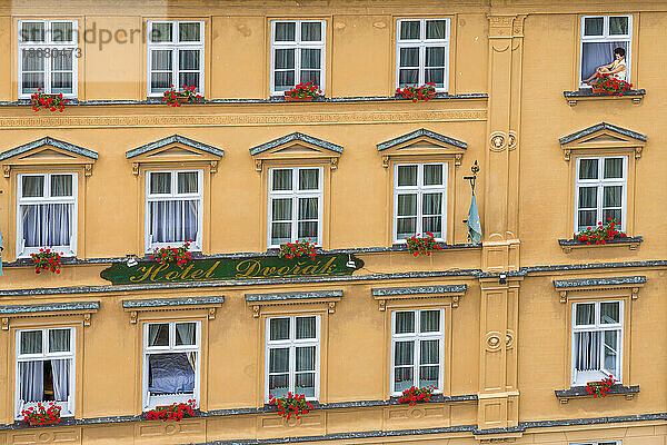 Frau sitzt im Fenster eines Hauses im historischen Zentrum von Cesky Krumlov  UNESCO-Weltkulturerbe  Cesky Krumlov  Südböhmische Region  Tschechische Republik (Tschechien)  Europa