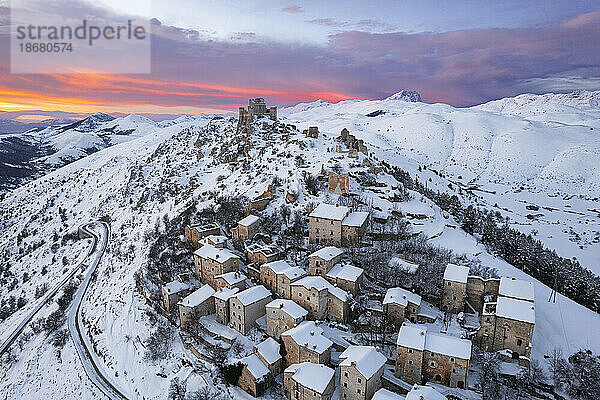 Winteransicht des verschneiten mittelalterlichen Dorfes Rocca Calascio mit der Burg auf dem Hügel in der Abenddämmerung  Rocca Calascio  Nationalpark Gran Sasso e Monti della Laga  Campo Imperatore  Provinz L'Aquila  Region Abruzzen  Italien  Europa