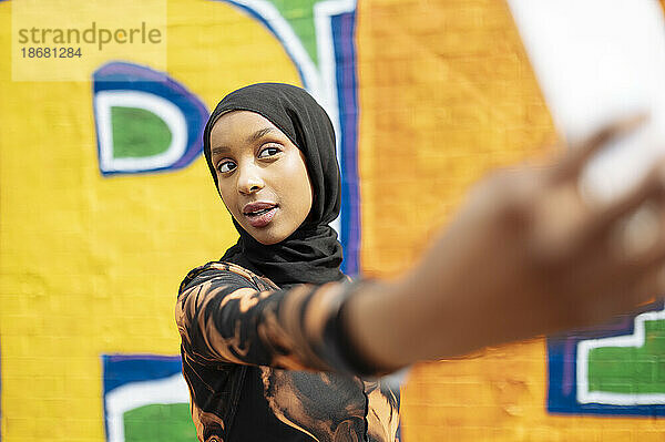 Junge Frau im Hijab macht ein Selfie auf der Straße