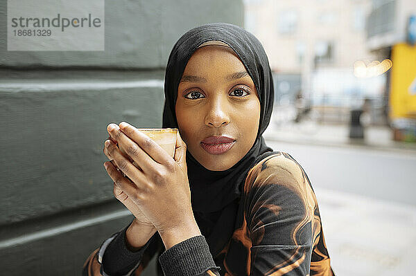 Porträt einer jungen Frau im Hijab  die Kaffee trinkt