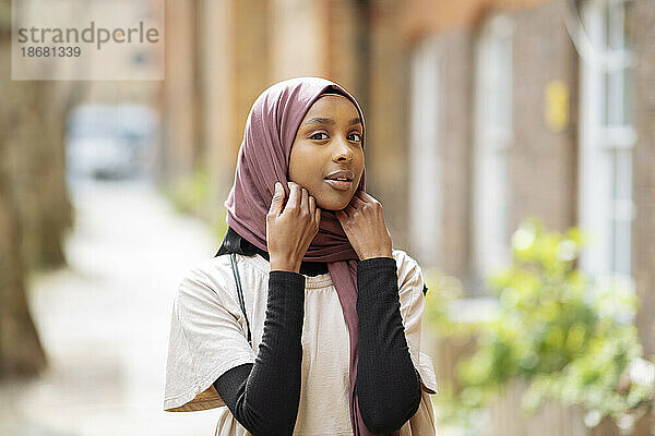 Porträt einer jungen Frau  die ihren Hijab anpasst