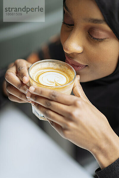 Junge Frau im Hijab trinkt Kaffee