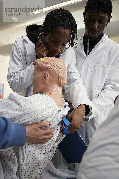 Medizinstudenten führen medizinische Untersuchung an einer Puppe durch