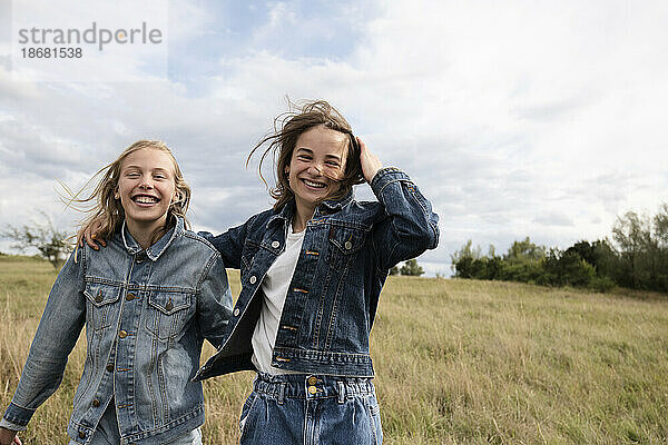 Lächelnde Freundinnen (10-11) tummeln sich im Feld