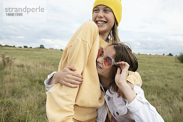 Lächelnde Freundinnen (10-11) mit modischen Accessoires