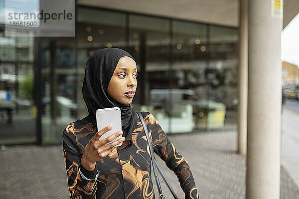 Junge Frau im Hijab benutzt Telefon in der Stadt