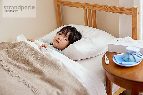 Japanisches Kind liegt krank im Bett
