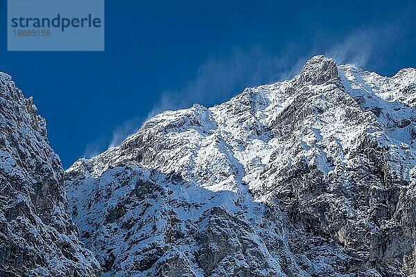 Es ist windig und kalt an den schneebedeckten Felshängen im Karwendel  der Himmel ist strahlend blau. Wintereinbruch Ende September