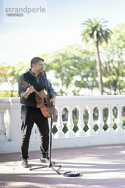 Musiker Mann spielt Gitarre und singt auf der Straße