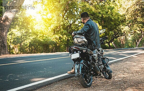 Motorradfahrer sitzt auf seinem Motorrad am Straßenrand. Mann auf seinem Motorrad sitzend am Straßenrand
