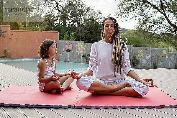 Blonde Rastamutter mit ihrer kleinen Tochter im Lotussitz. Meditation und Entspannung