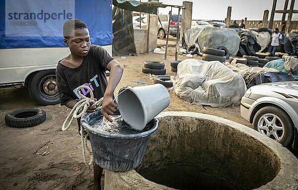 Junge schöpft Wasser aus einem Brunnen auf einem Industriegelände  Lome  Togo  15.06.2021.  Lome  Togo  Afrika