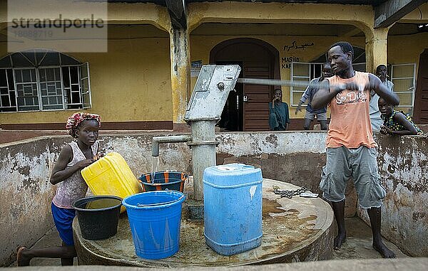 Bomeh Village auf der KissyRoad Müllkippe. Mädchen und Mann an der Wasserpumpe  die nur giftiges Wasser liefert  Freetown  15.06.2021. Auf den Müllbergen der Stadt haben die Ärmsten der Armen angefangen zu siedeln. Sie leben über giftigen Dämpfen und mit verdrobenem Wasser.  Sierra Leone  Afrika