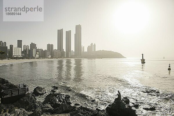 Haeundae Strand  Busan  Südkorea  Stadt am Meer  Leute  Besucher  Morgenlicht  Sonnenaufgang  Wahrzeichen  Statue in Bucht  Silhouette  Wanderweg am Wasser  Asien