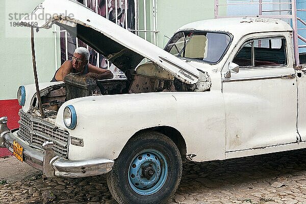 Kubanischer Automechaniker repariert einen amerikanischen Chrysler Pickup aus den 1950er Jahren auf der Straße in Trinidad  Kuba  Karibik  Mittelamerika