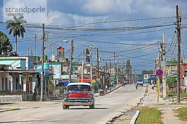 Roter amerikanischer Oldtimer bei der Fahrt durch die Stadt Jatibonico  Provinz Sancti Spíritus auf der Insel Kuba  Karibik