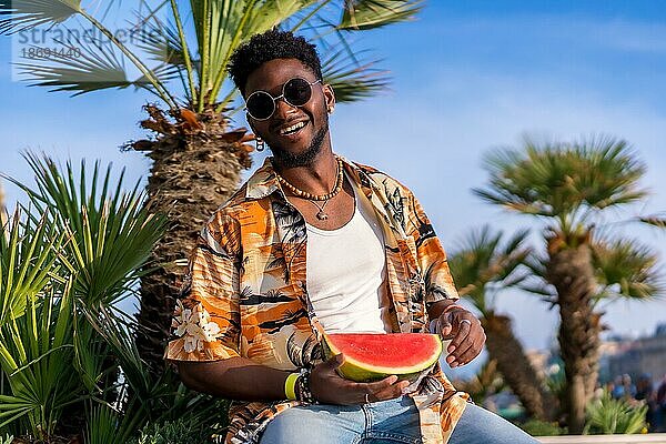 Porträt eines schwarzen ethnischen Mannes genießen Sommerurlaub am Strand mit einer Wassermelone Spaß haben