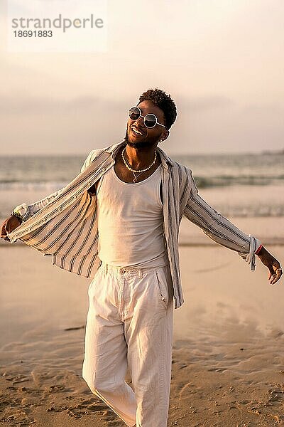 Porträt eines attraktiven schwarzen ethnischen Mannes  der seinen Sommerurlaub am Meer genießt und sich frei fühlt