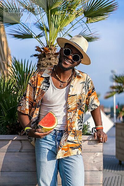 Porträt eines schwarzen ethnischen Mannes genießen Sommerurlaub am Strand  Schatten und eine Wassermelone