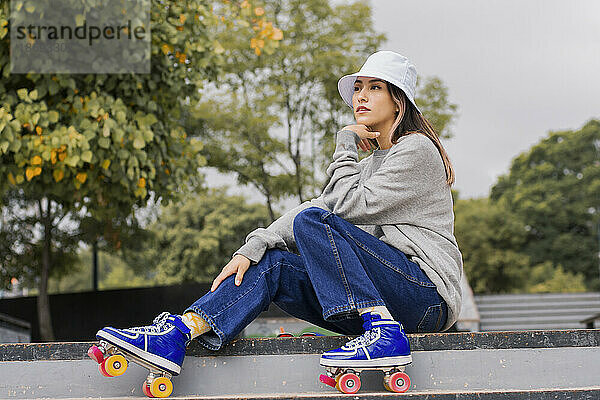 Nachdenkliche junge Frau sitzt auf Stufen im Park