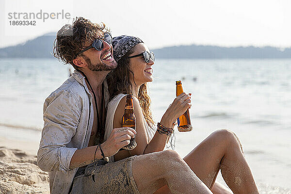 Glückliches Paar beim Bier am Strand