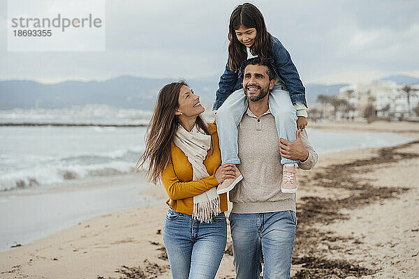 Glückliche Familie  die gemeinsam an der Küste am Strand spaziert