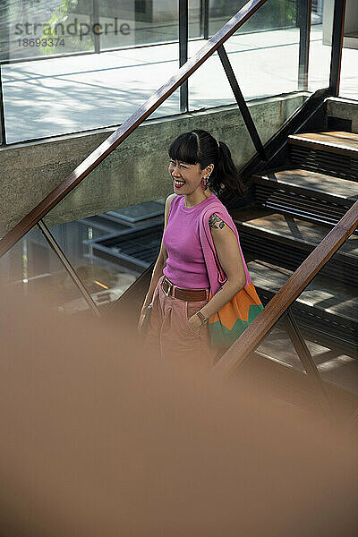 Glückliche Frau mit Tasche steht auf der Treppe