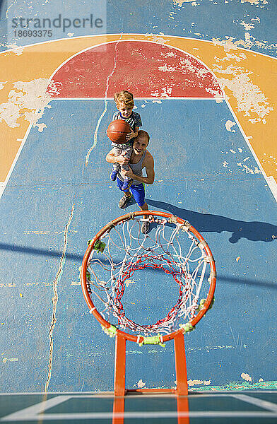 Sohn und Vater spielen Basketball auf dem Sportplatz