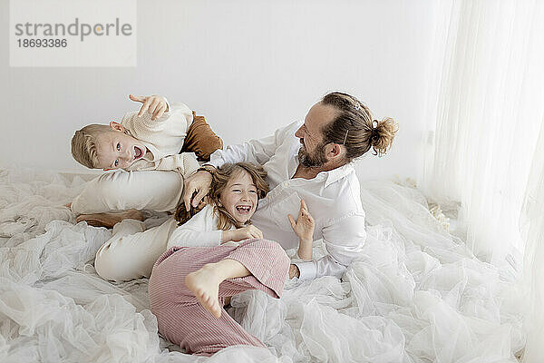 Father having fun with son and daughter in front of wall