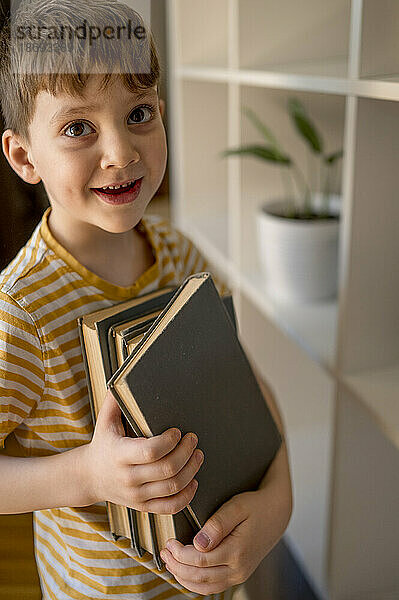 Lächelnder Junge  der zu Hause Bücher hält