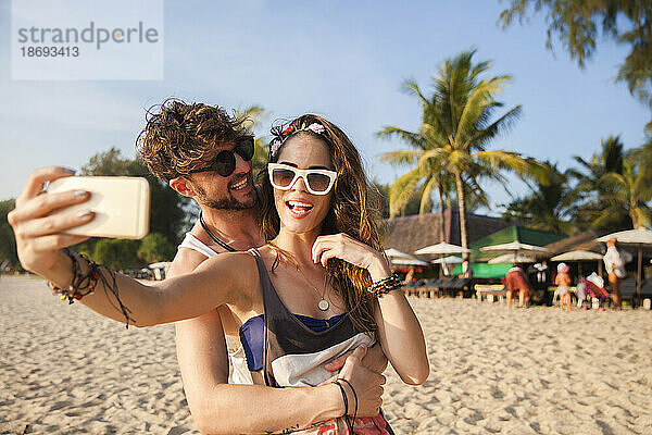 Frau macht mit ihrem Freund am Strand ein Selfie per Smartphone