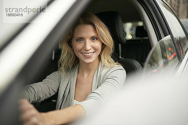 Lächelnde blonde Frau  die Auto fährt