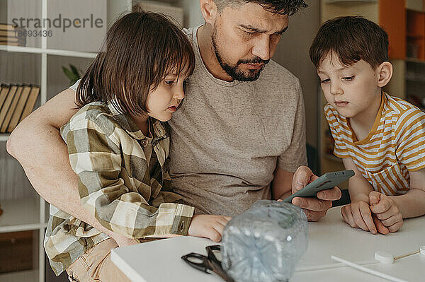 Vater teilt Smartphone mit Söhnen zu Hause