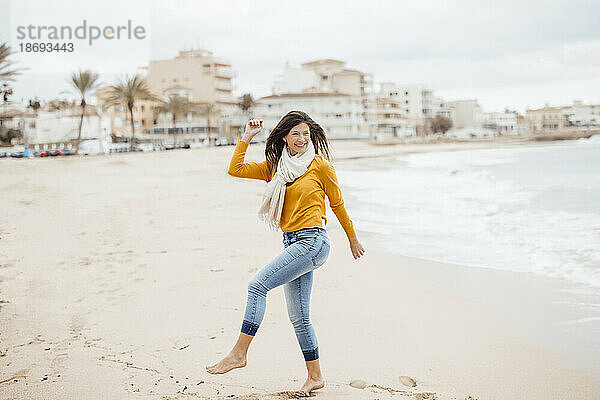 Glückliche Frau tanzt an der Küste am Strand