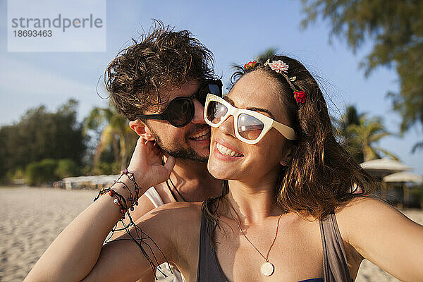 Glückliches Paar mit Sonnenbrille am Strand