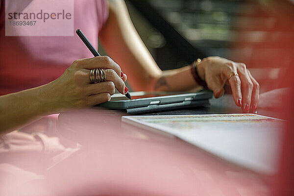 Hand einer Frau mit digitalisierter Stiftzeichnung auf einem Grafiktablett