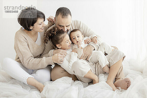 Glückliche Familie genießt das gemeinsame Sitzen vor einer weißen Wand