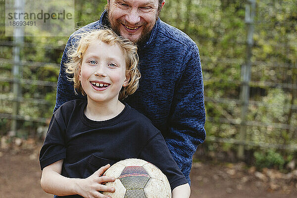 Vater umarmt glücklichen Sohn mit Fußball